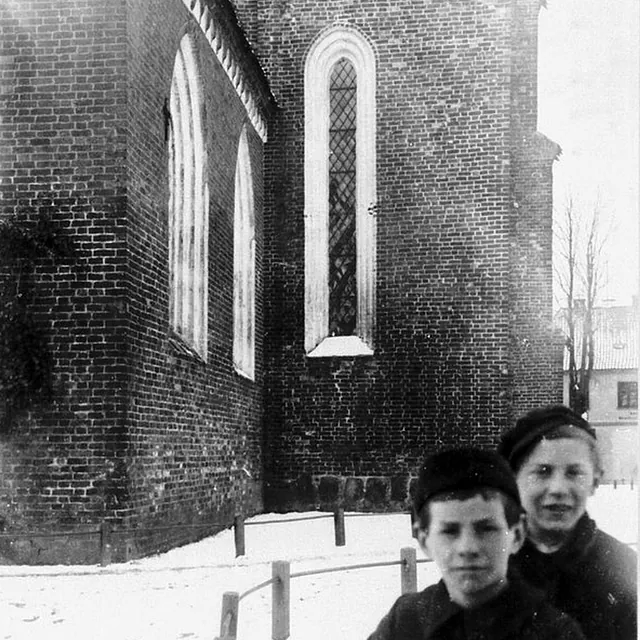 Kirchenmauer im Winter mit zwei Jungen im Vordergrund.