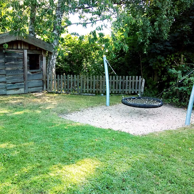 Spielplatz mit Nestschaukel und Holzhaus